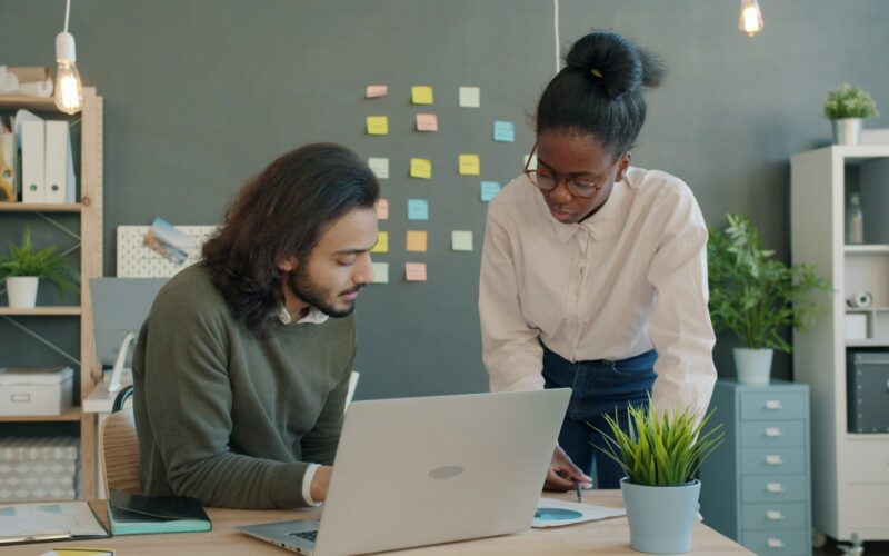 Two colleagues reviewing numbers together at a desk in a bright office.