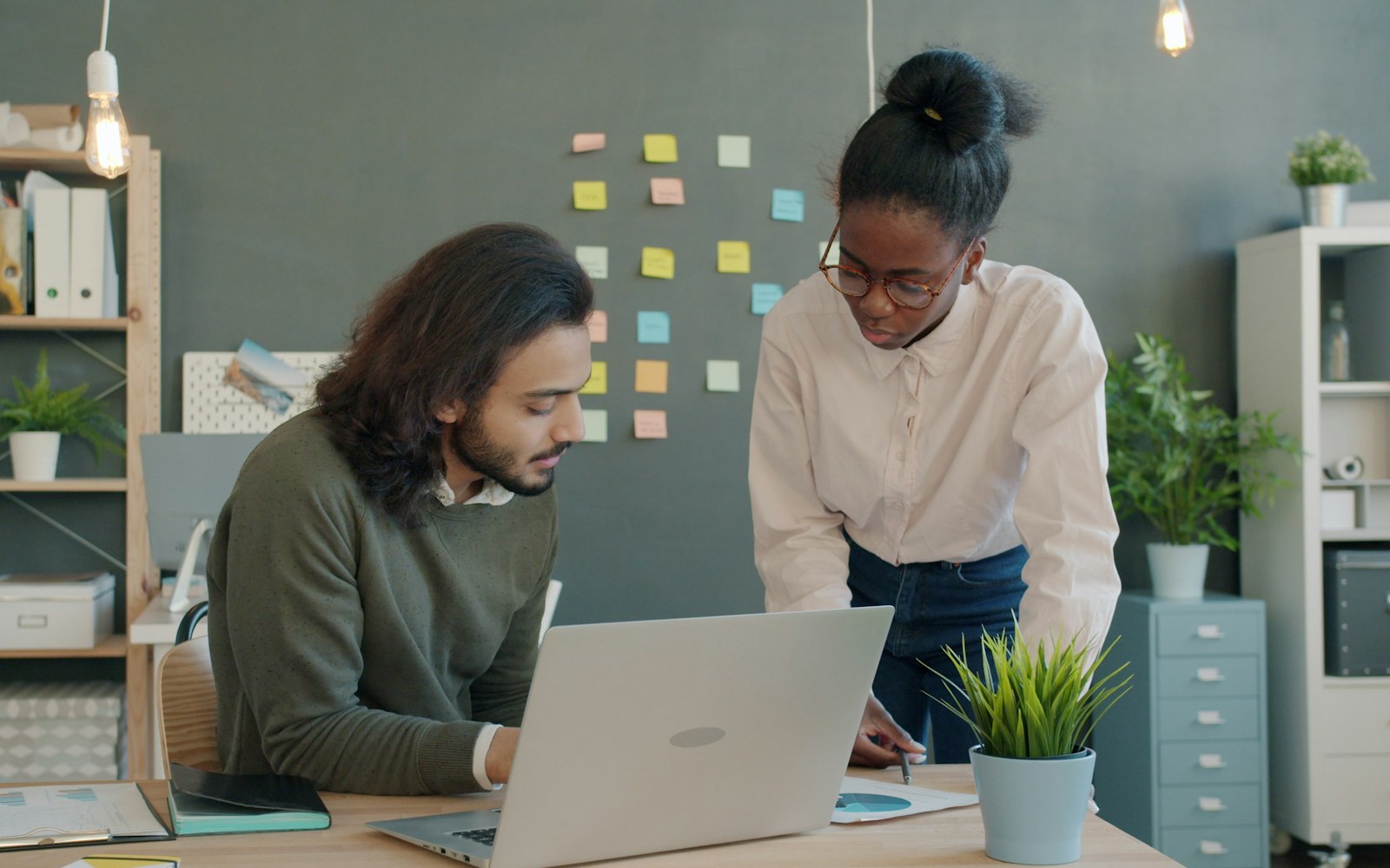 Two colleagues reviewing numbers together at a desk in a bright office.