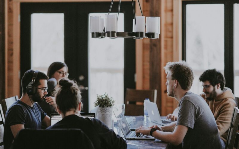 A small team talking around a wooden table in a bright room.
