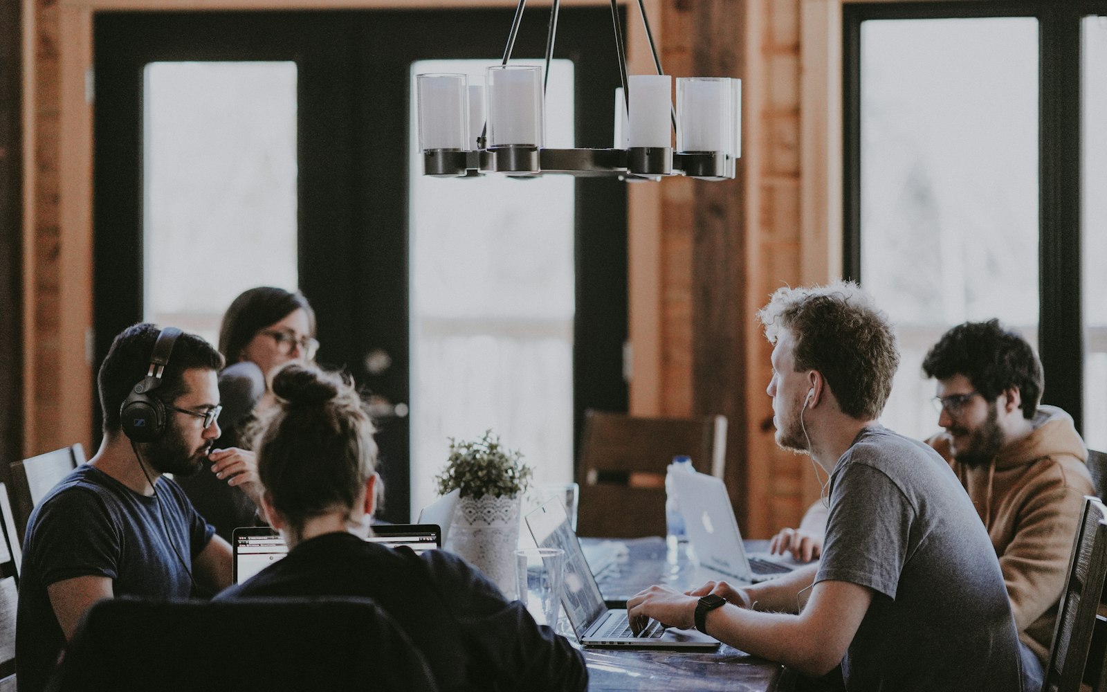 A small team talking around a wooden table in a bright room.