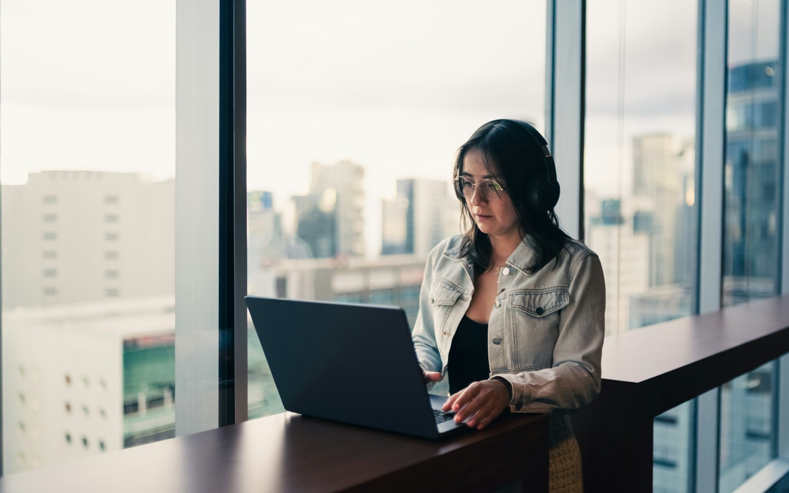 A business owner thinking through options on a laptop by a bright window.